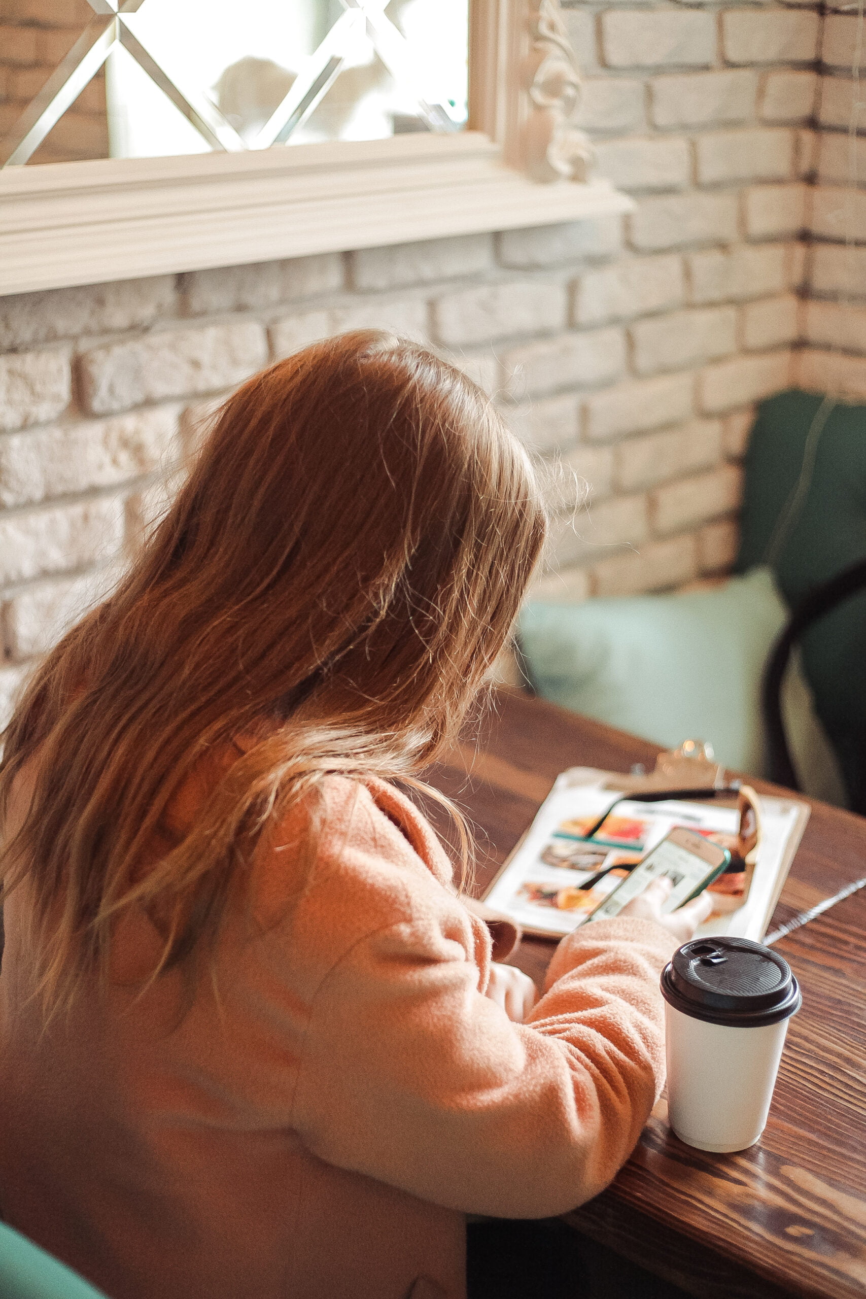 Woman working in a coffee shop, typing on her mobile phone.